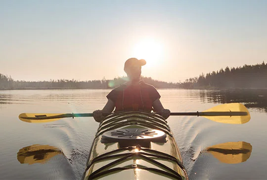 Kajakpaddlare i solnedgång
